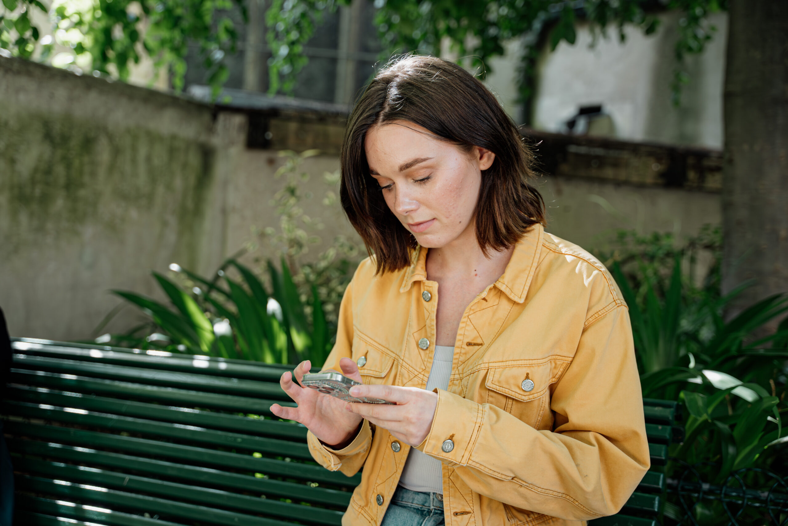 une jeune fille blouson jaune consulte son téléphone