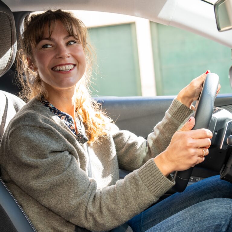 candidate d'auto-école au volant souriante par une belle journée ensolleillée