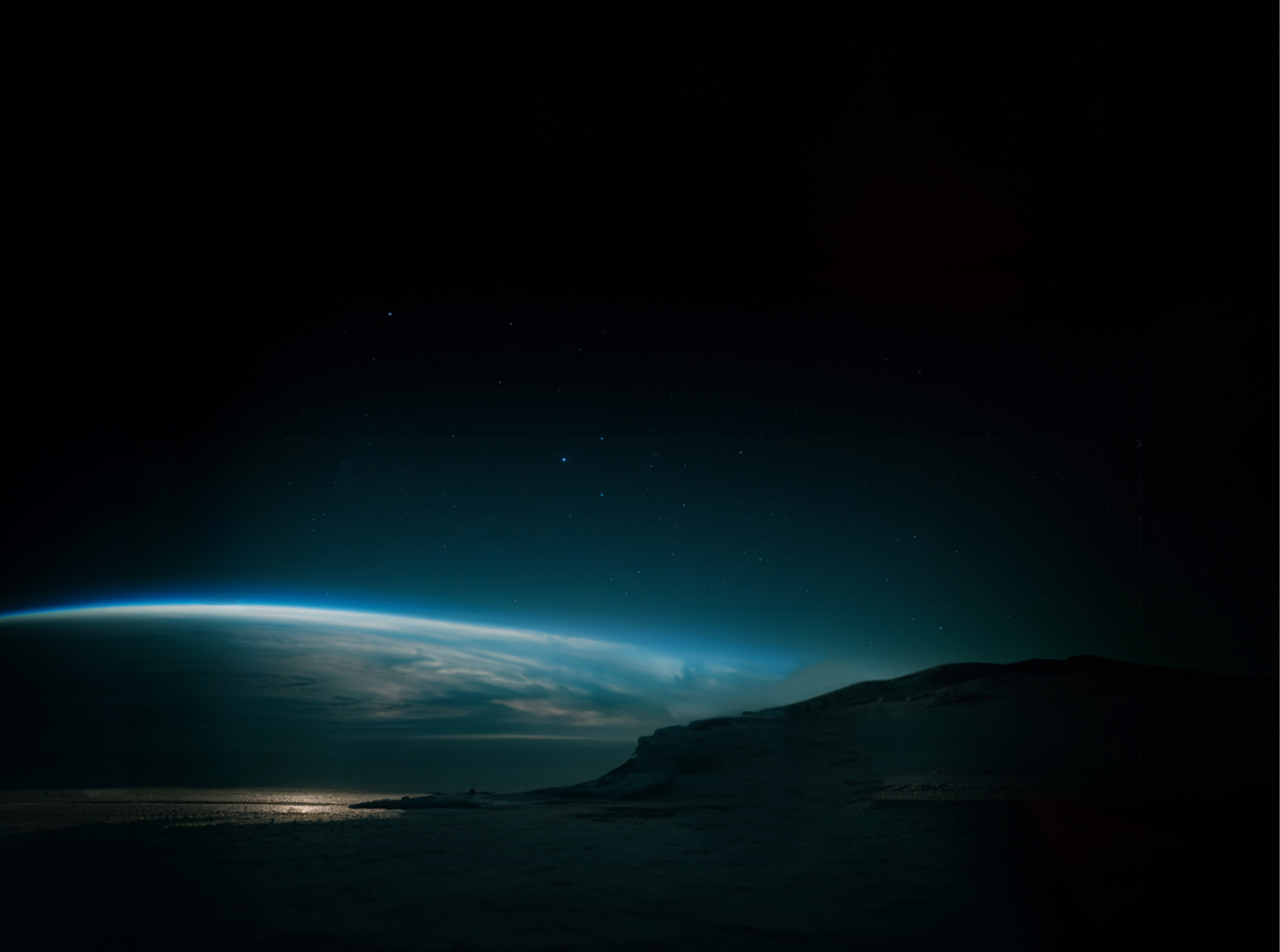 Vue de l’horizon avec la lumière bleutée de l’atmosphère et un ciel étoilé.
