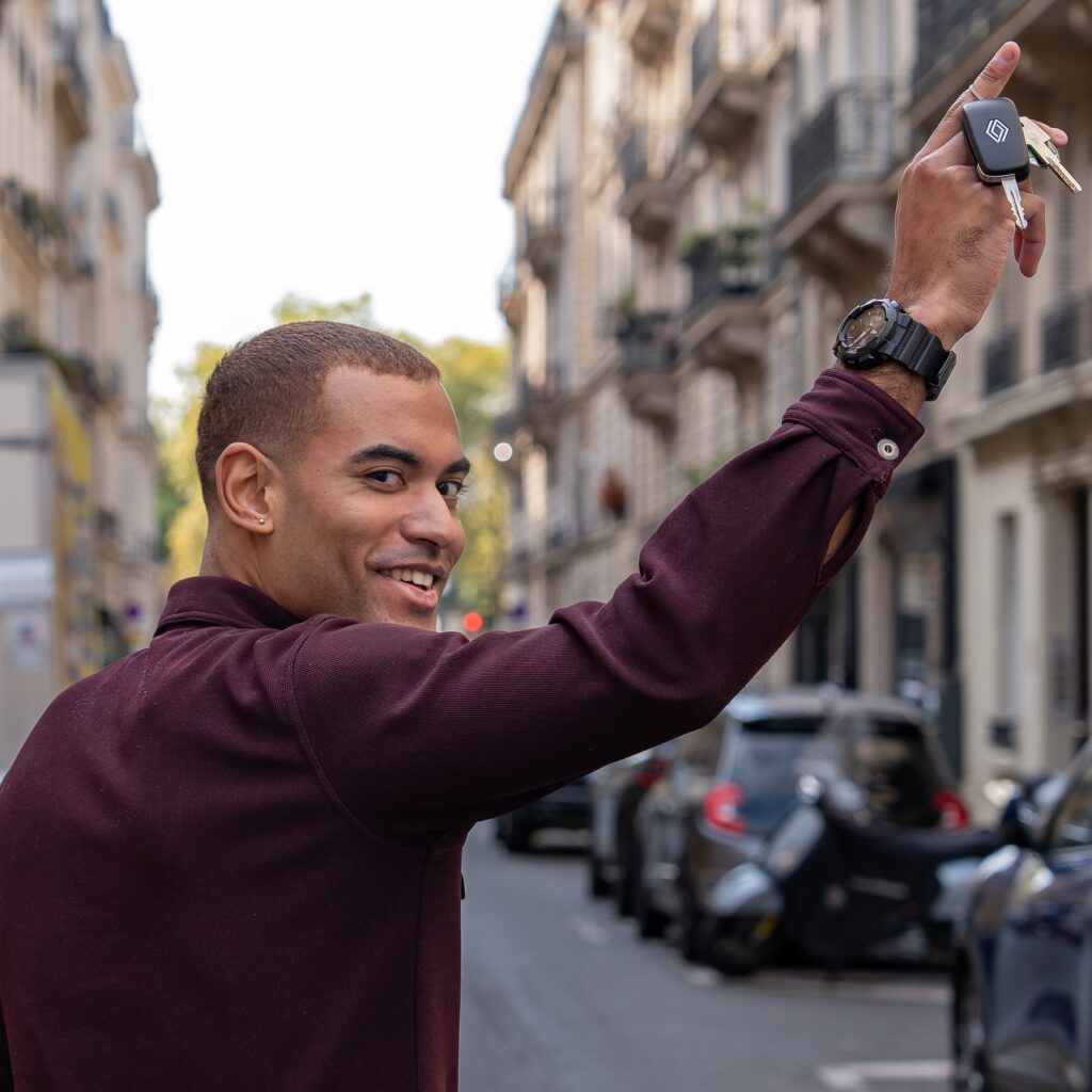 dans la rue , un hjeune homme brandit ses clés de voiture