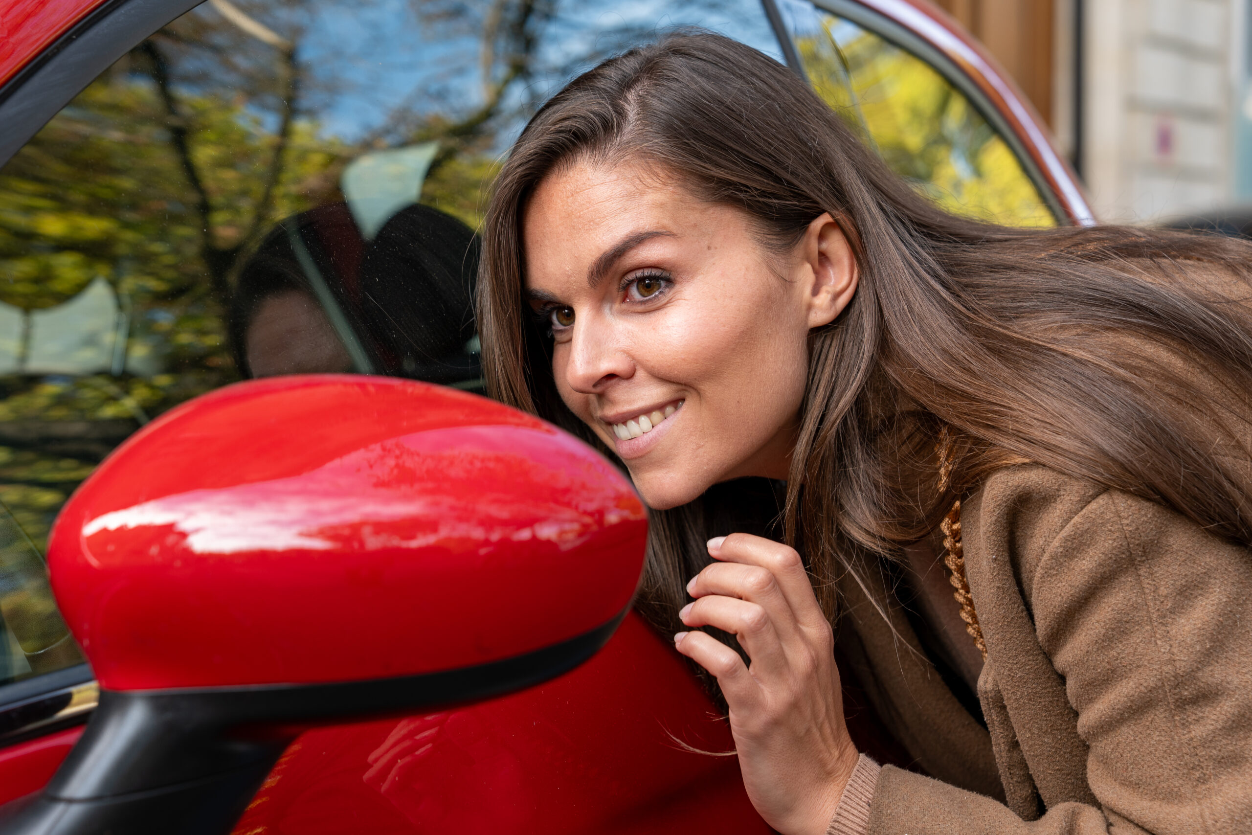 une jeune femme se regarde dans le rétroviseur d'une voiture