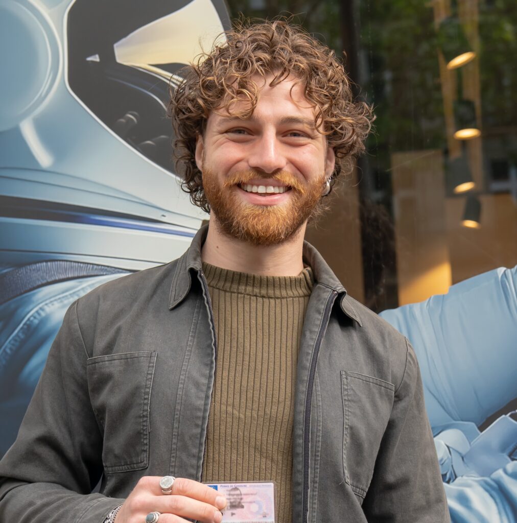 jeune homme souriant , permis en main, devant l'auto-école La Navette Paris 17