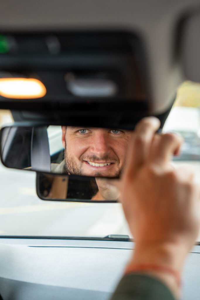 élève en cours de conduite, règle un rétroviseur de la voiture
