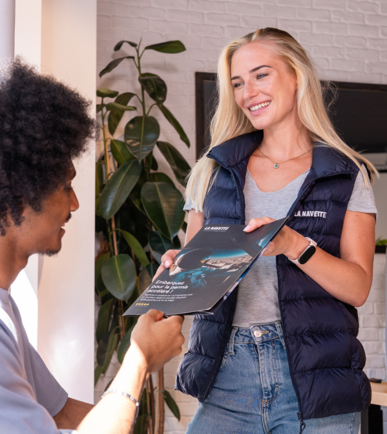 Commercial qui donne la documentation La Navette à un élève